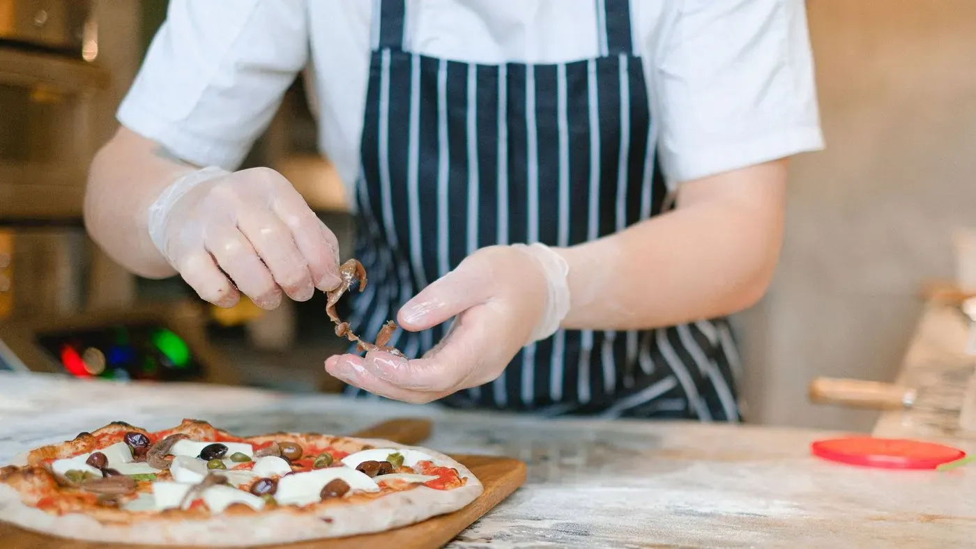 Pizzaspade av trä bredvid en pizza